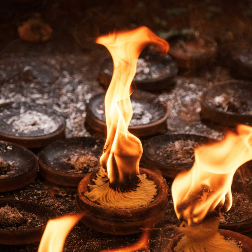 A close up of lit diyas, kept inside a small claypot, on the ground in Tirupati.