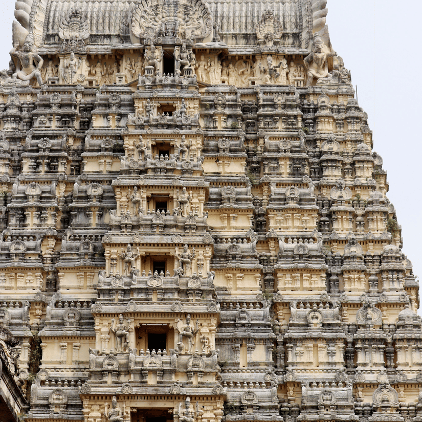 A view from below of a temple's facade with intricate art on the exterior of the roof in Tirupati.