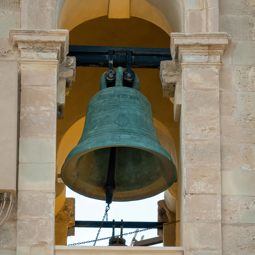 A historic bell suspended on a mounted structure, rung by pulling a string.