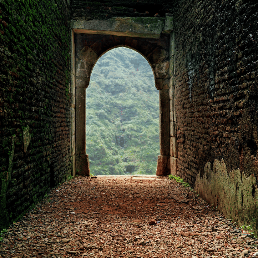 Stone arched gateway of a historic fort with sunlight filtering through a vaulted ceiling.