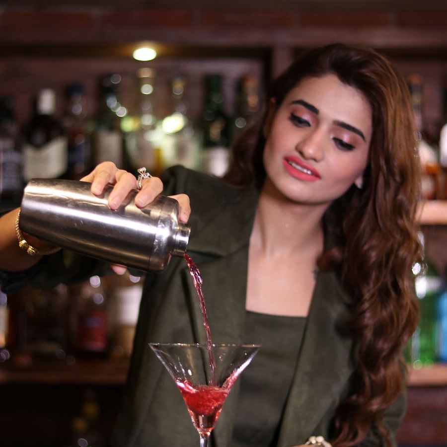 Heritage Village Manesar - image of a woman in a suit pouring a red coloured cocktain into a martini glass