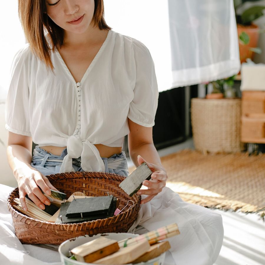 a woman holding a block print with other block prints in a basket