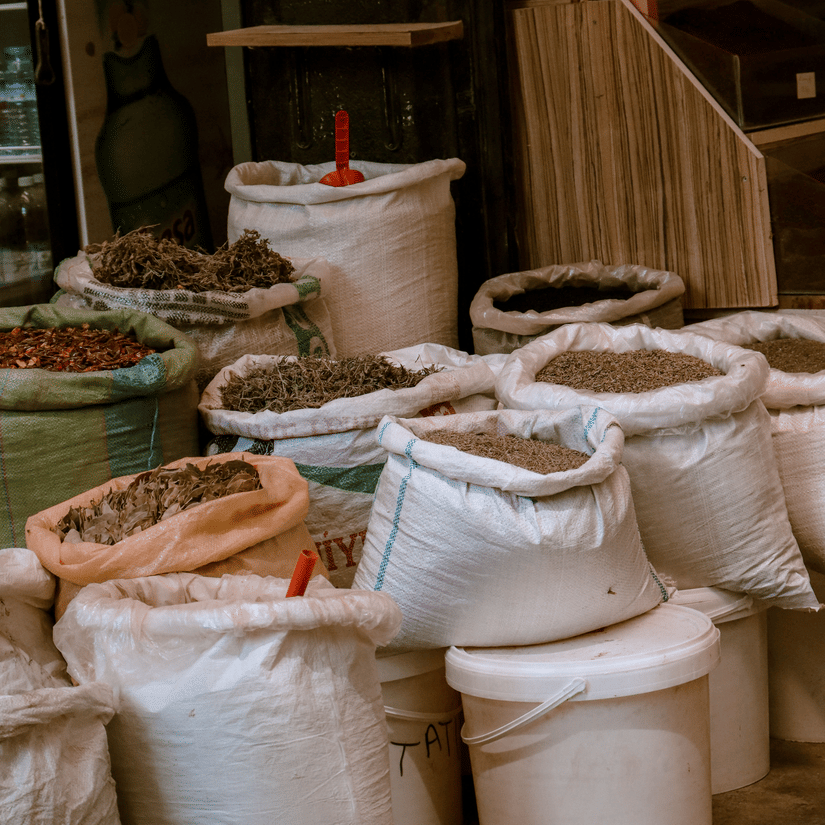A close up of a street shop in Mercato Market with numerous types of spices being sold in gunny bags.