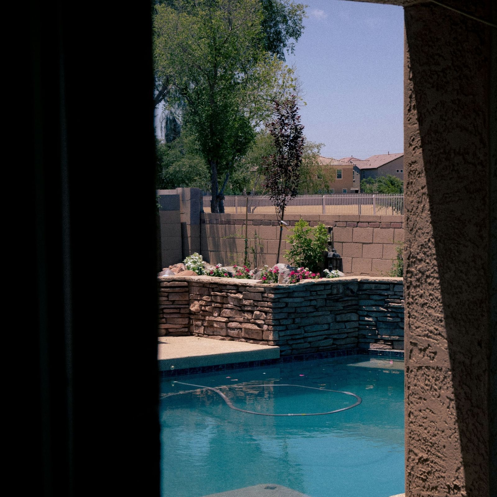Balcony or terrace area with a wooden roof, railing, and lush green surroundings.