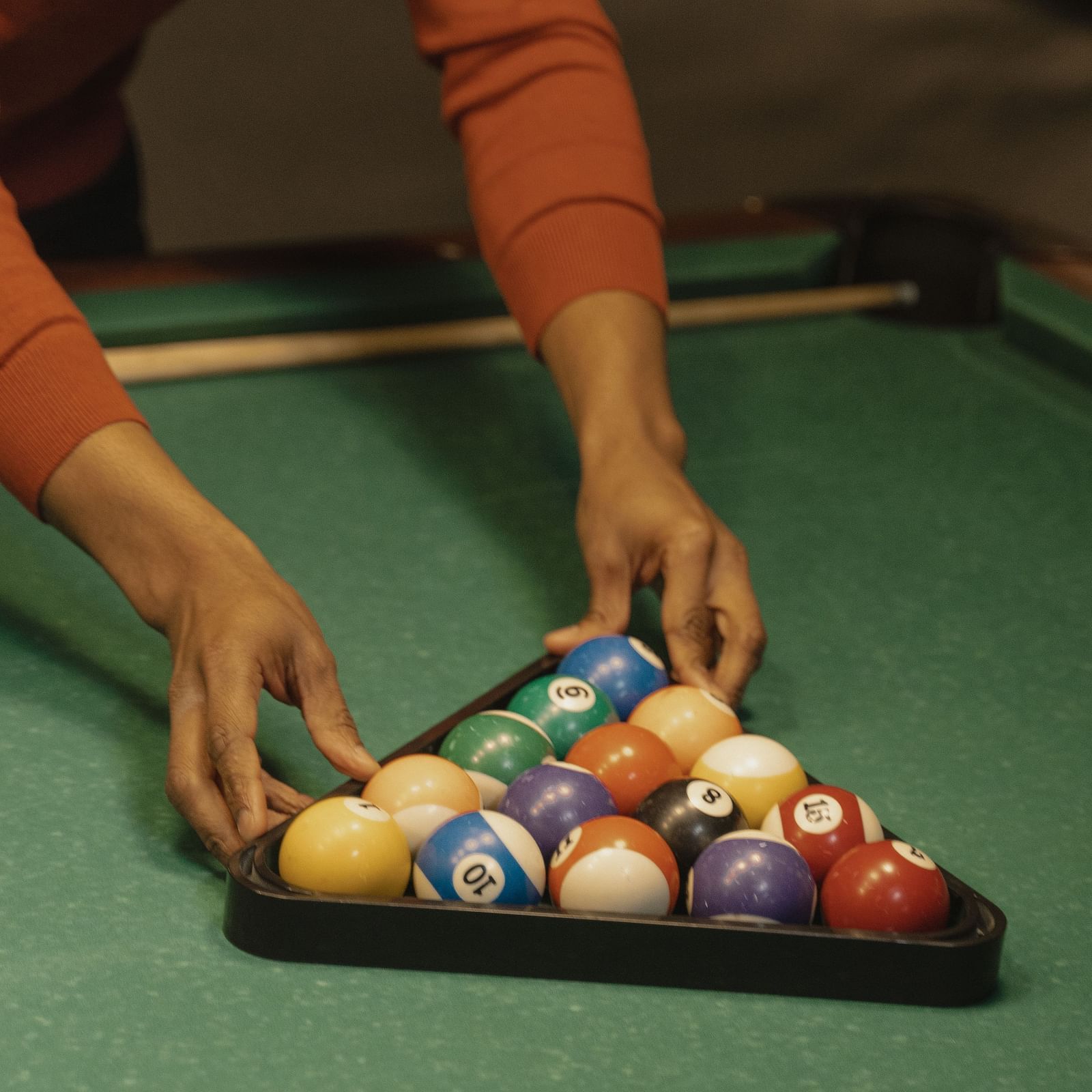 A hand arranging pool balls at a Pool Table