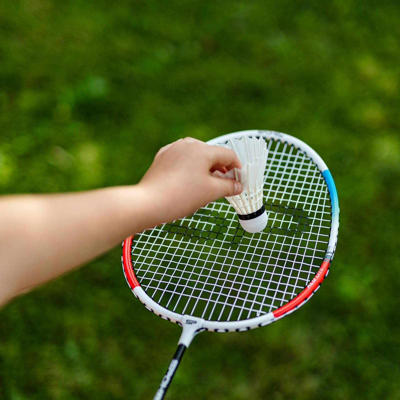 image of a badminton racket with a shuttle cock against a beautiful grass