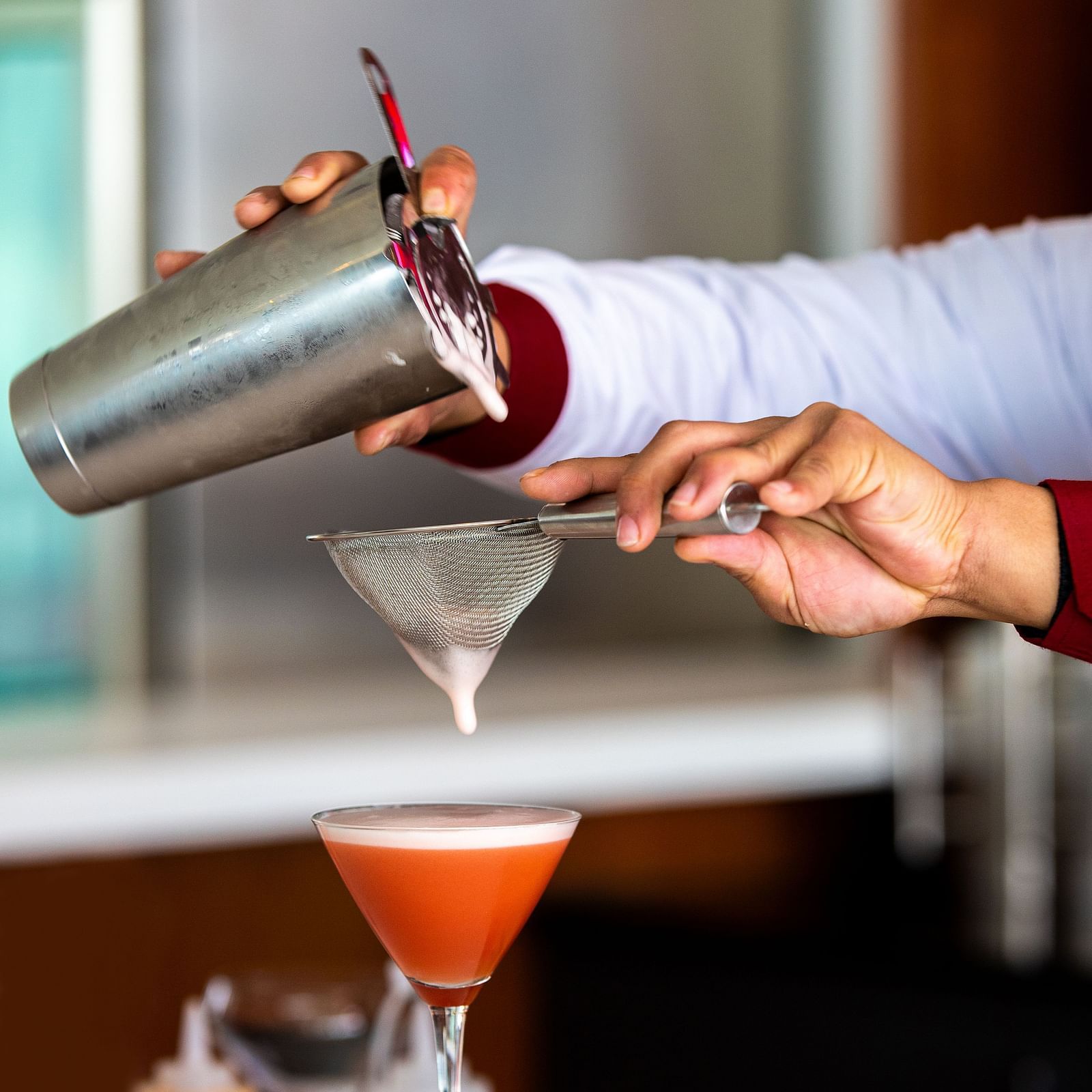 Portrait shot of two hands pouring a drink from a shaker and straining it into a martini glass at Mandala Norling Lords Prime, Kathmandu.