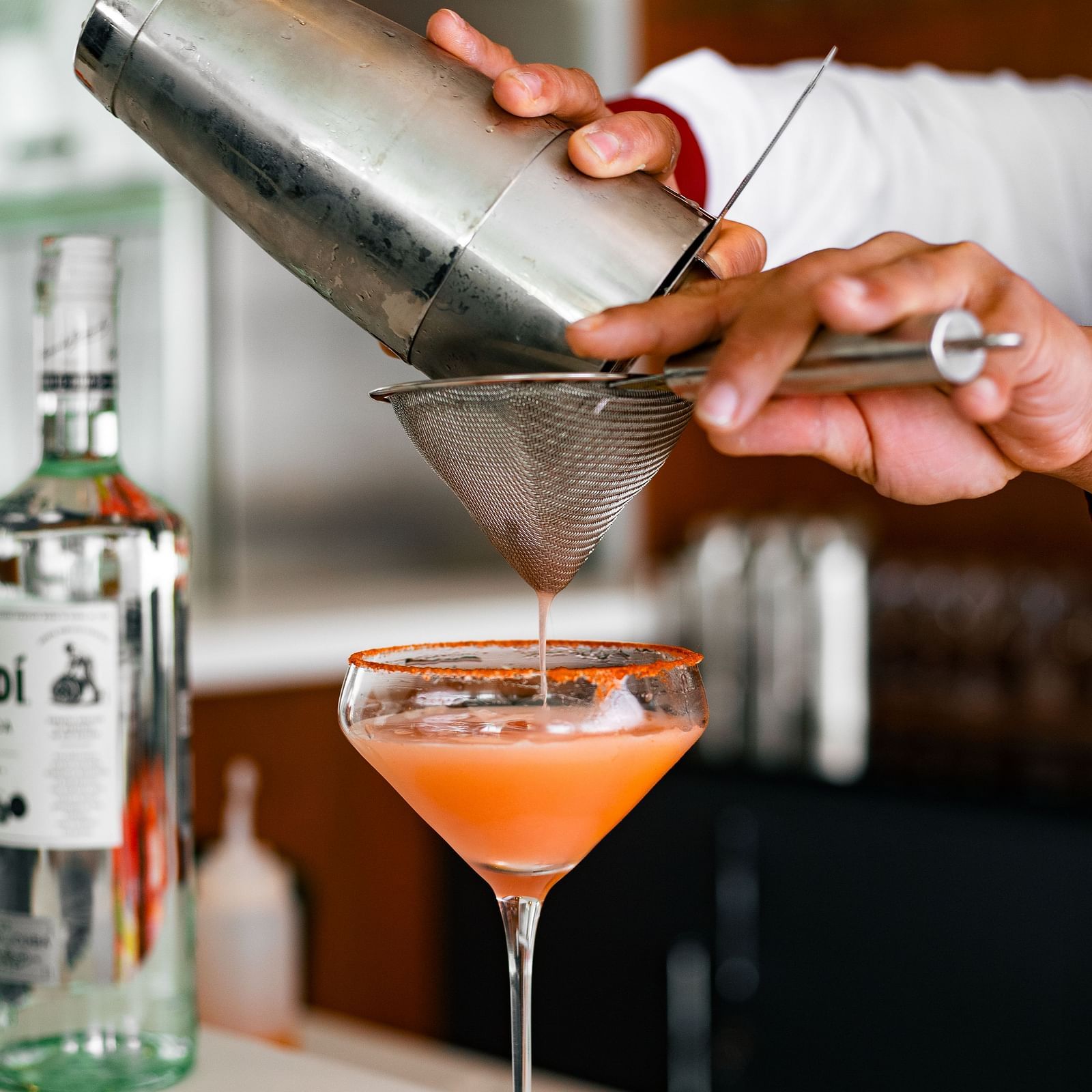 Portrait shot of two hands pouring a drink from a shaker and straining it into a martini glass at Mandala Norling Lords Prime, Kathmandu.