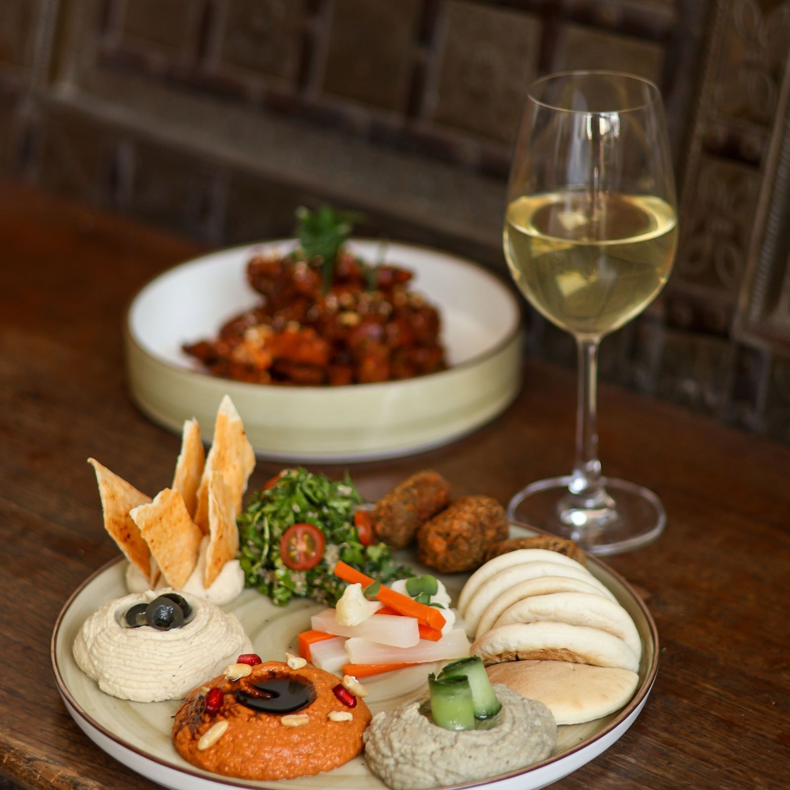 Mediterranean platter with hummus, falafel, pita, and wine served at Panna Vilas Palace, presented on a rustic wooden table.