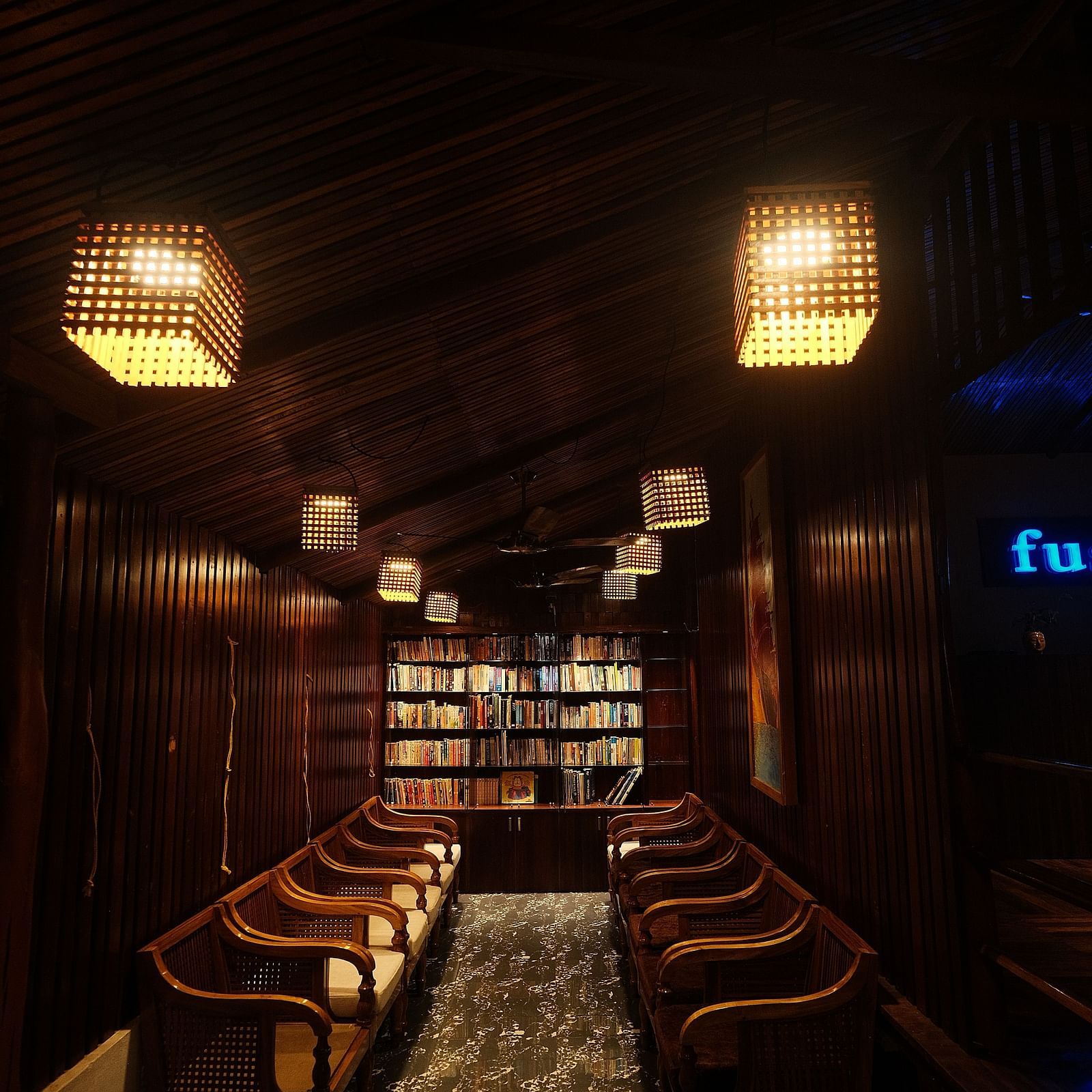 A dimly lit view of the restaurant's counter area with rows of chairs nearby | Fusion Cafe and Multi-cuisine | RainForest Resort, Port Blair, Andaman and Nicobar Island