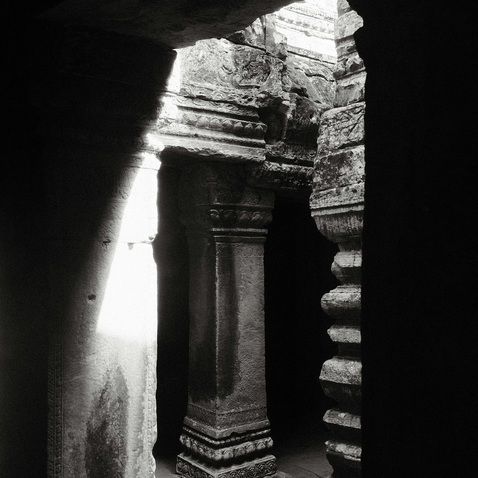 Ancient temple interior with stone pillars and a view of the sanctum through a narrow passage