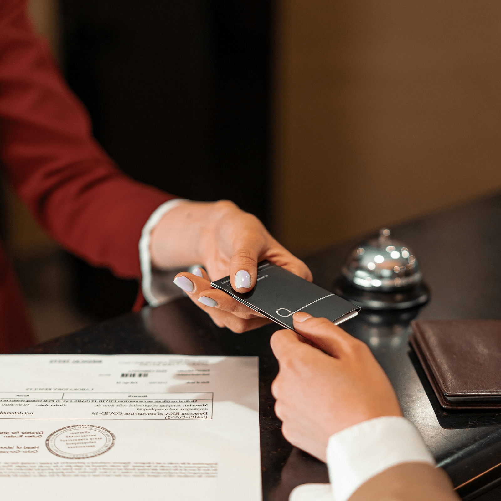 A person handing over their passport to the front desk executive at a hotel