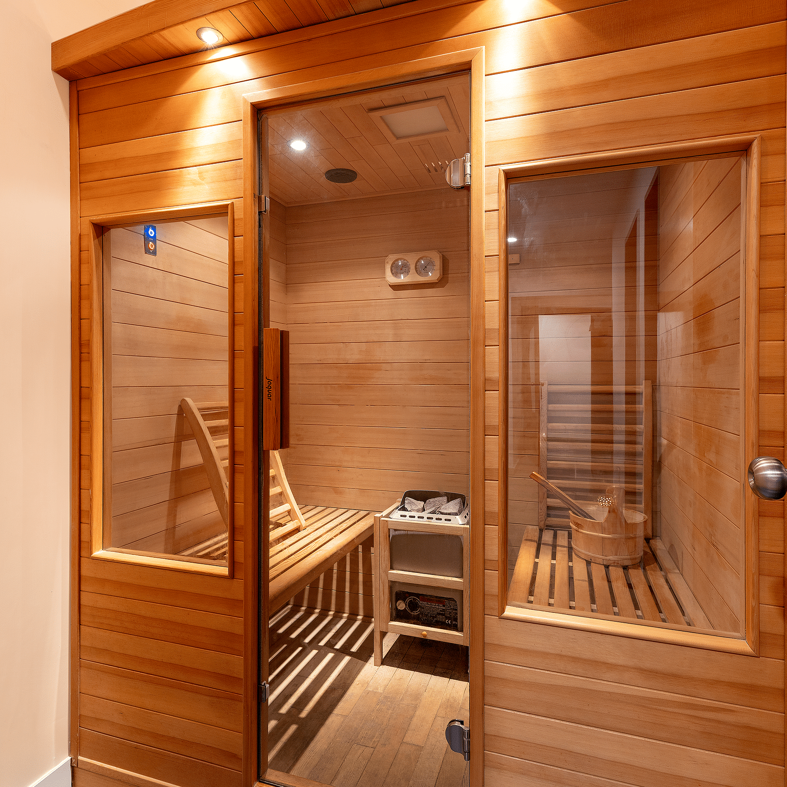 A wooden sauna with a glass door and side panels, lit from above - Via Lakhela Resort & Spa, Kumbhalgarh