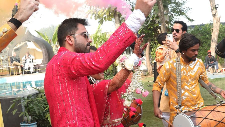 Man in red traditional attire throwing coloured powder during a celebration at Tisya Farms, Gurgaon.