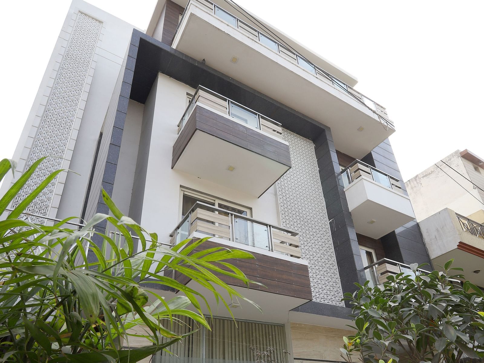An exterior shot of a contemporary building with angular design and greenery visible in the foreground - Asian Suites Cyber Park, Gurgaon