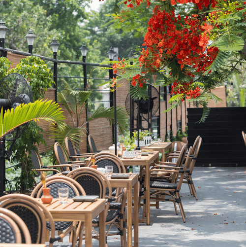 Outdoor seating with chairs under red flowers at Polo Floatel Kolkata.