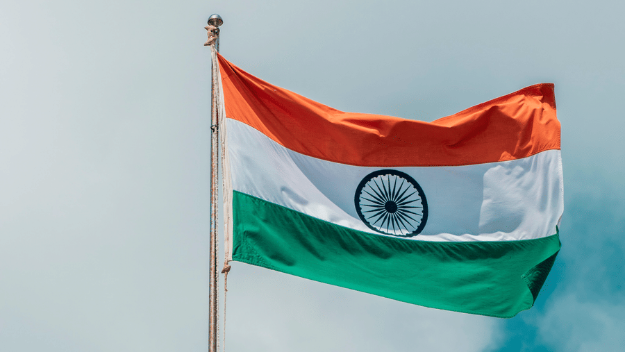 Indian national flag waving against a cloudy blue sky, symbolising patriotism and the spirit of Independence Day celebrations in India.