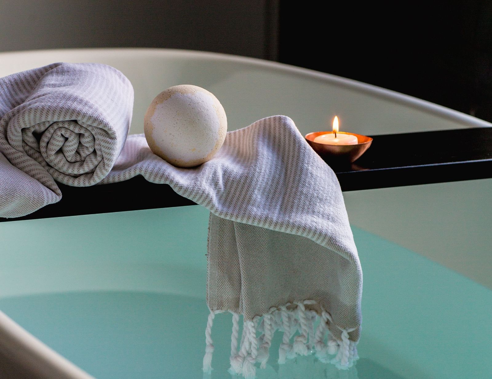 A tub filled with water along with towels and a candle
