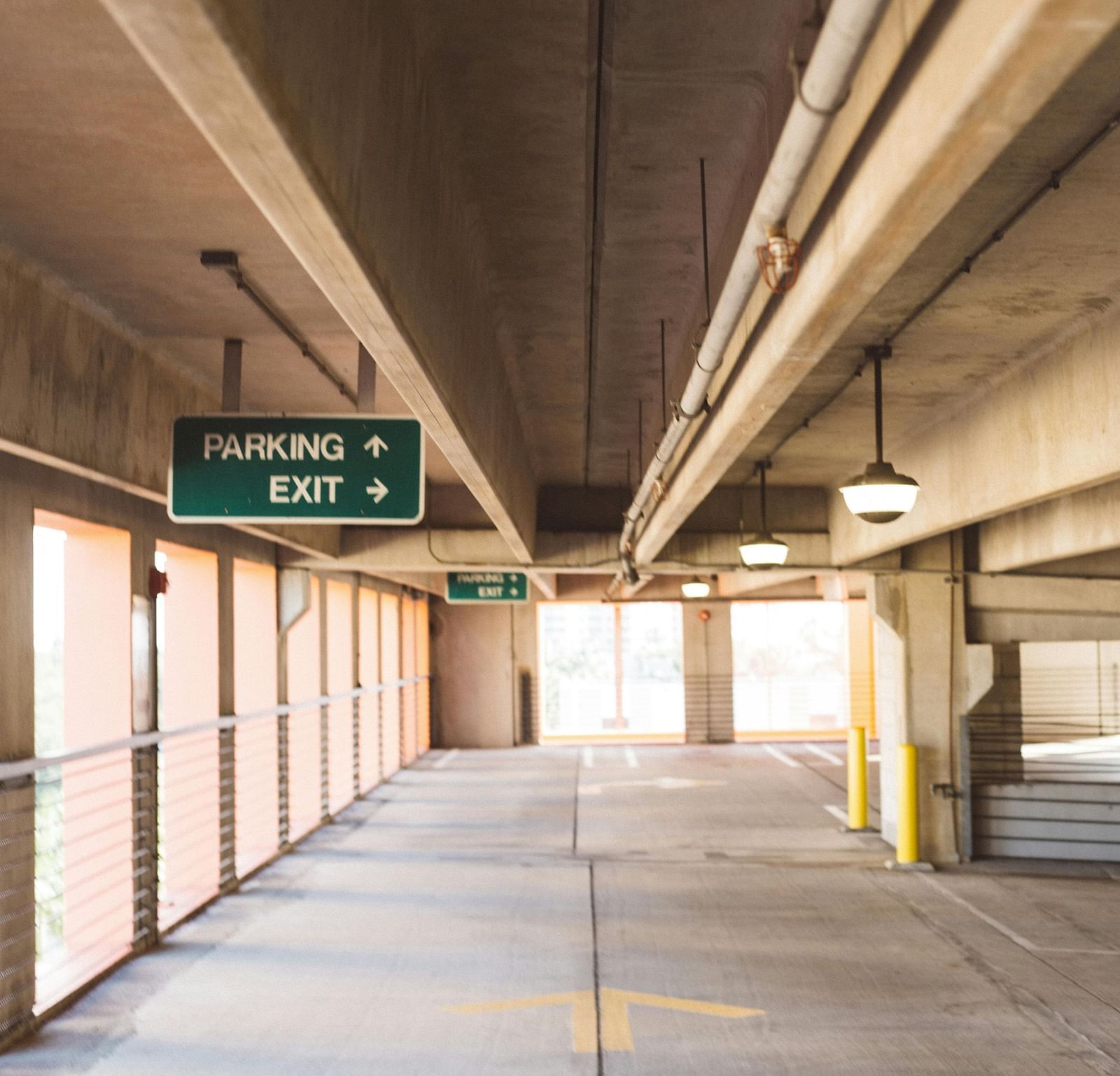 A spacious parking space with yellow coloured guiding arrows on the floor.