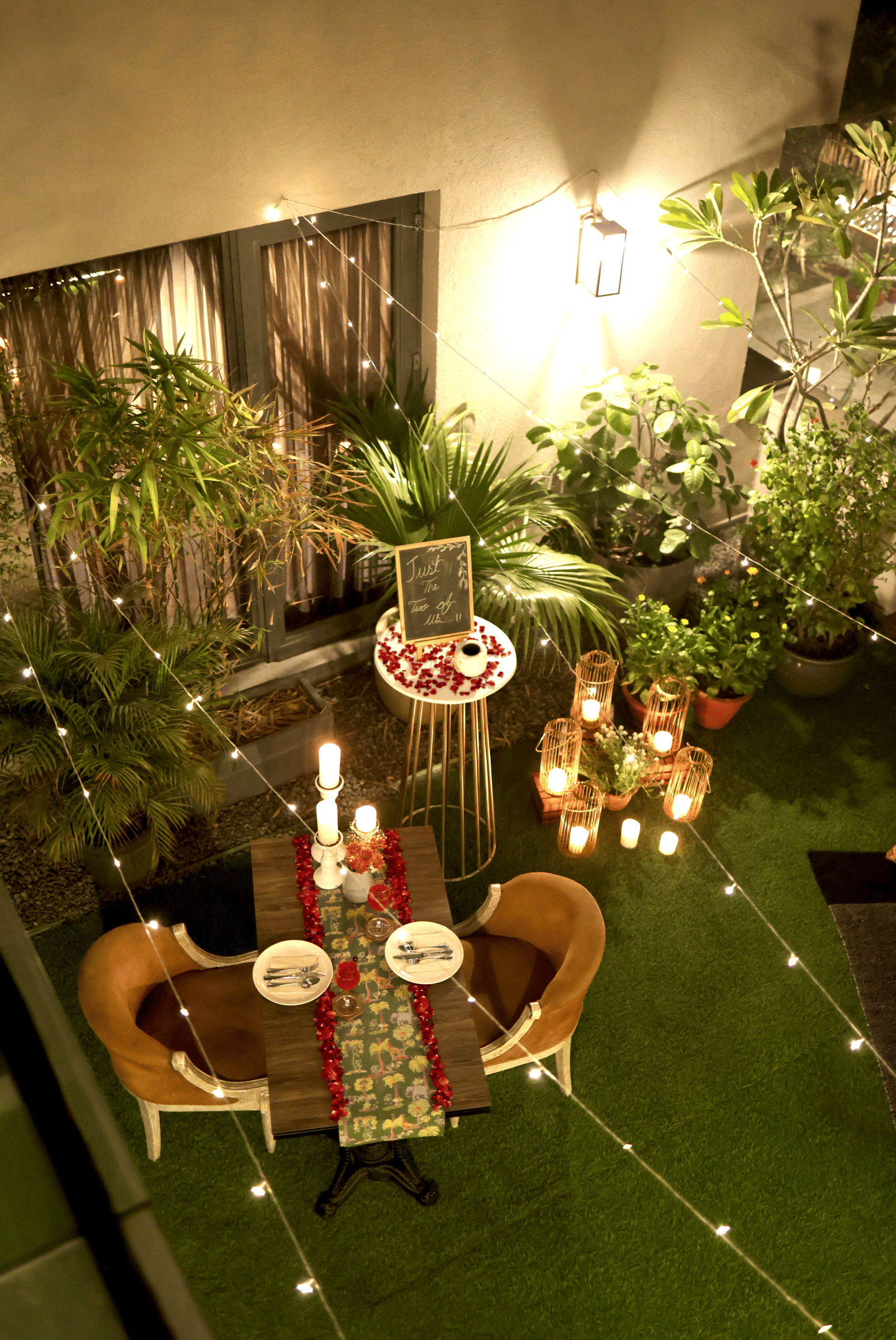 An intimate outdoor dining setup at night with candles, floral décor, and 2 chairs facing a small table at Karma Chalets.