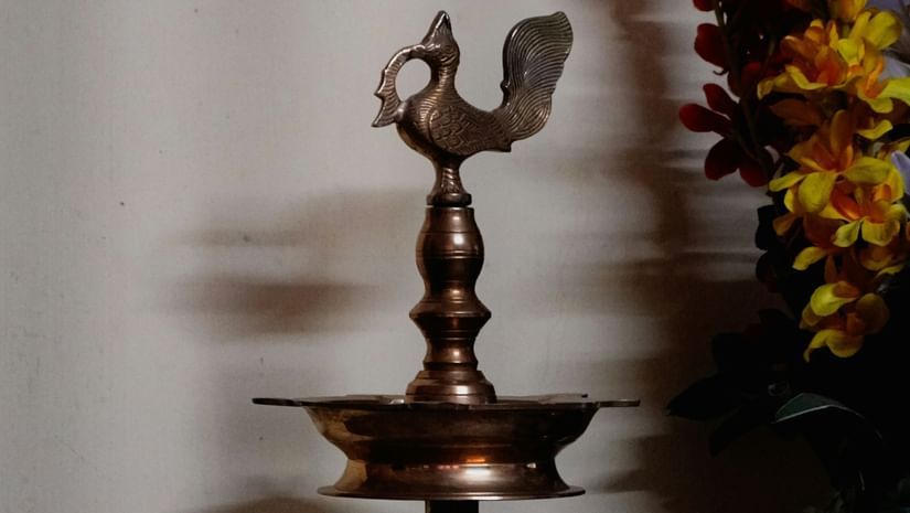 A brass oil lamp with a peacock design