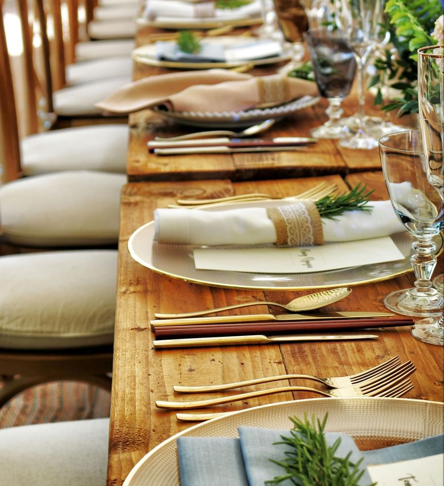 A long dining table arranged with plates, glasses, and cutlery.