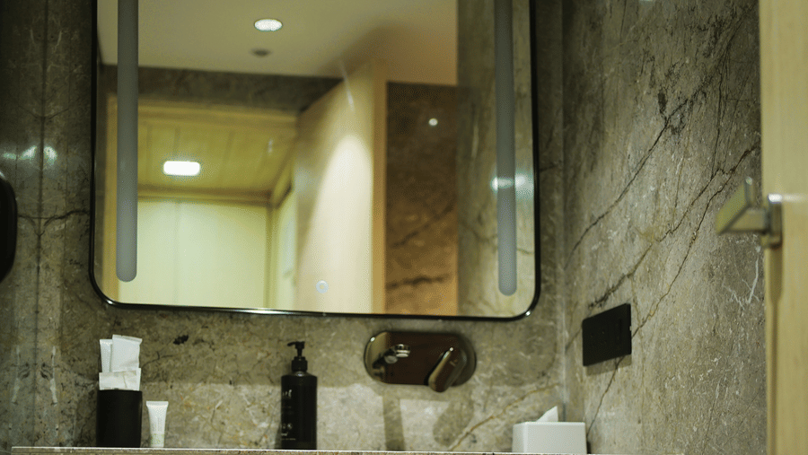 Infiniti Hotel, Indore | A washroom with a mirror and toileteries.