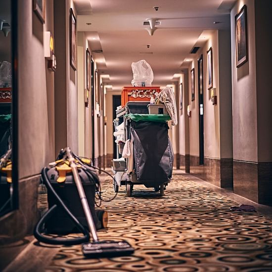 A picture of a garbage tin, broom and vacuum cleaner can in the corridor