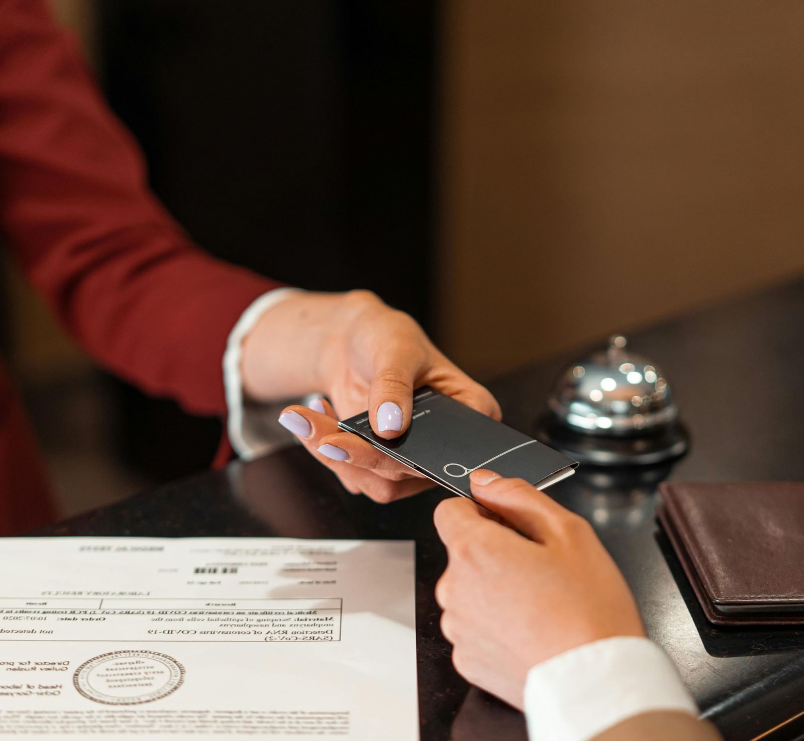 The receptionist handing over the key card to a guest over the front desk.