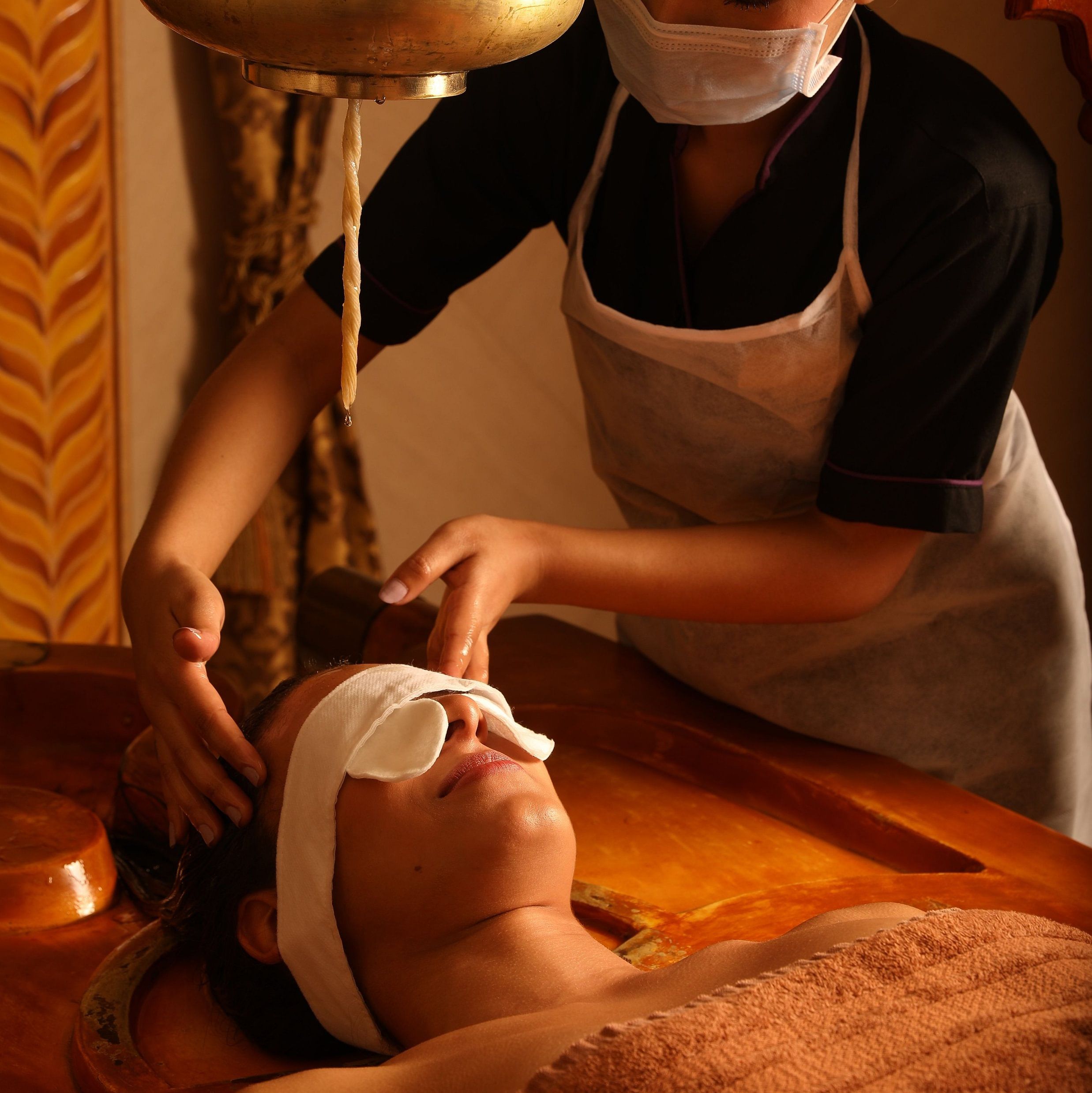 masseur performing shiro abhyangam on a guest