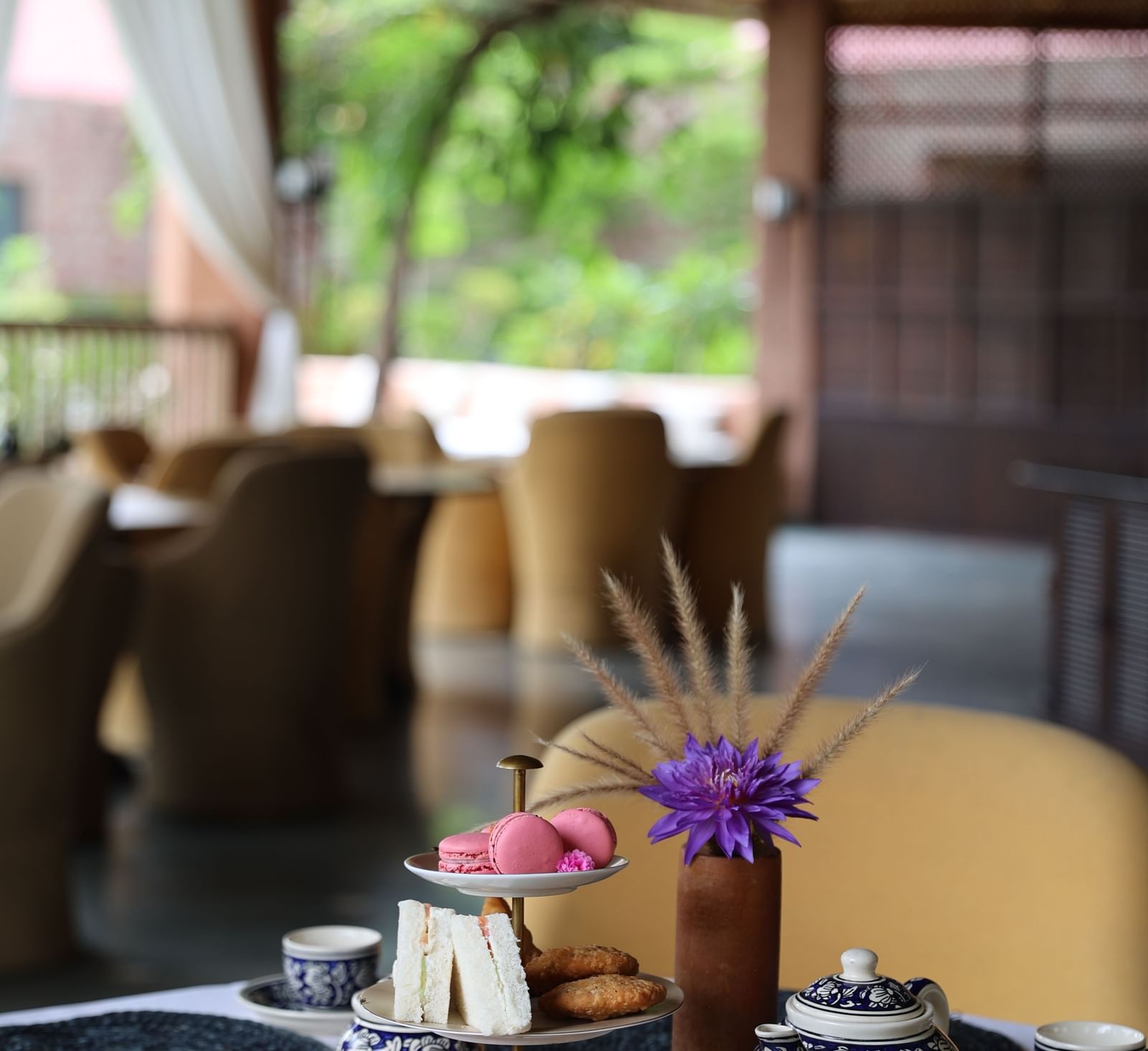 A set table at Surpura Bagh with a three-tier stand of macarons and croissants, and blue and white patterned teacups.