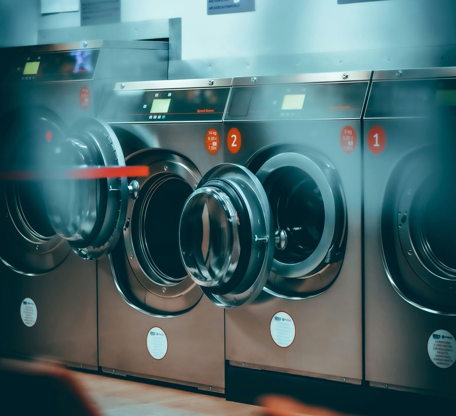 A row of industrial washing machines in a commercial laundromat