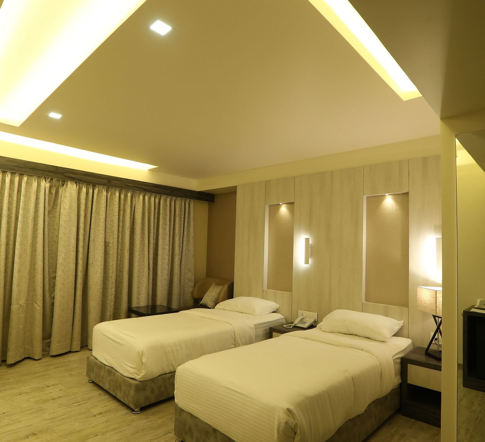 Executive Room with a vanity area, including a mirror and a sink, illuminated by warm lighting, with a chair and beige wall visible.