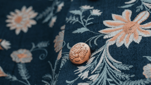 Close-up of embroidered floral fabric with decorative buttons.