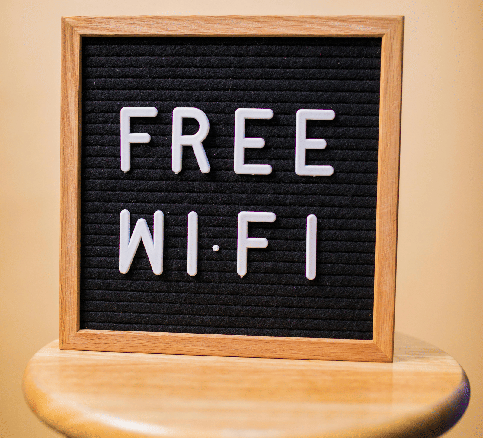 A close-up shot of a black letter board on a small wooden stool, displaying the text 'FREE WI-FI'.