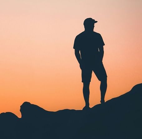 A person standing on a stone placed near a beach during a sunset - Brewery Gulch Inn & Spa
