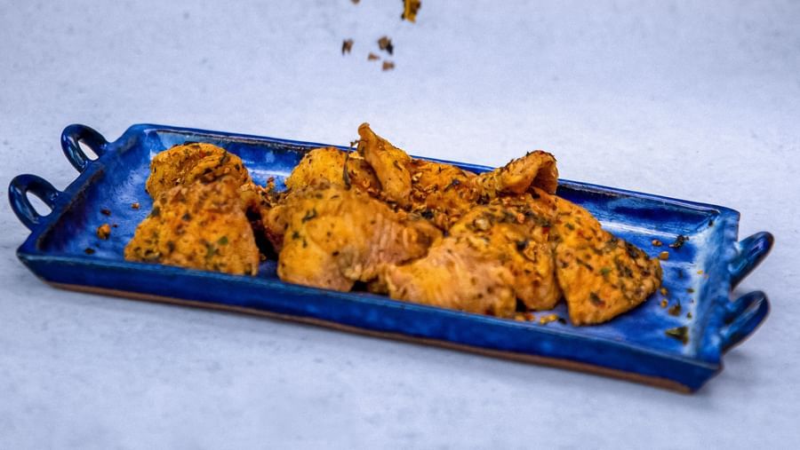 A hand sprinkling something on a tray of appetiser at The Hamuse Hotel, Kodaikanal.