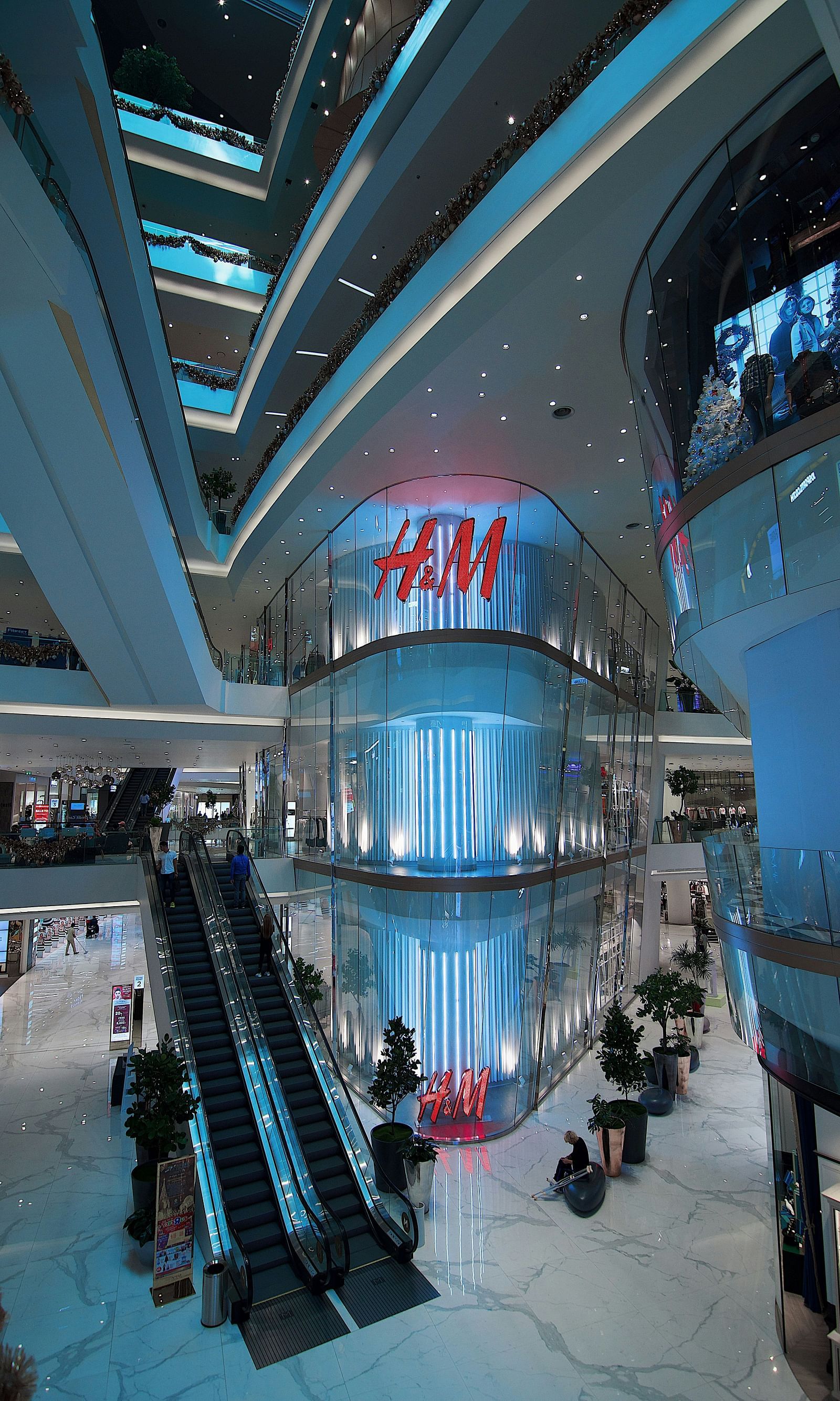 The mall area features escalators and cool lighting, creating a modern atmosphere