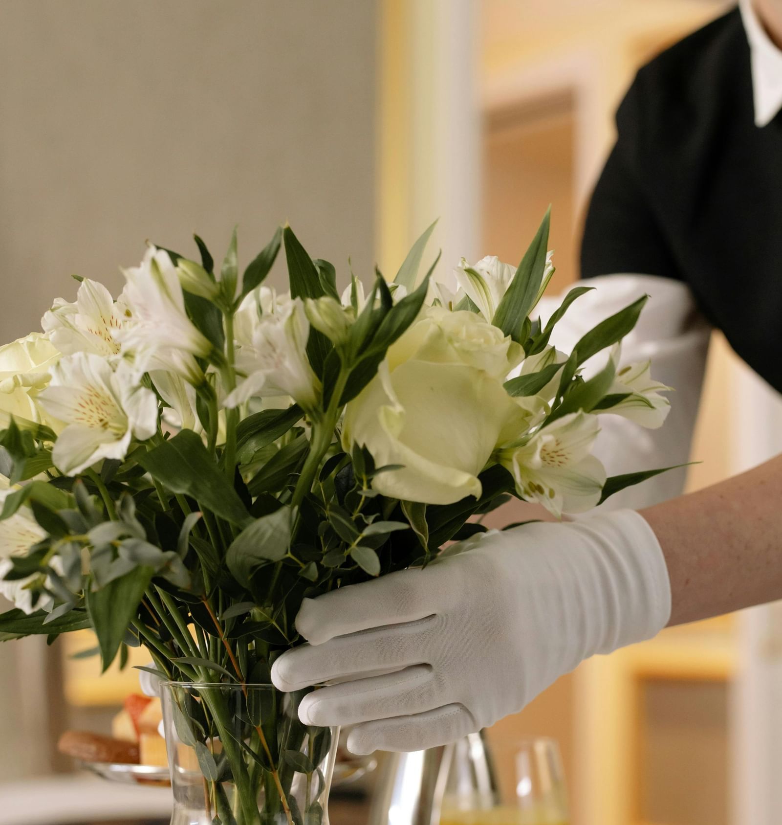 Hotel staff arranging flowers in a vase with tea service tray reflecting warm hospitality.