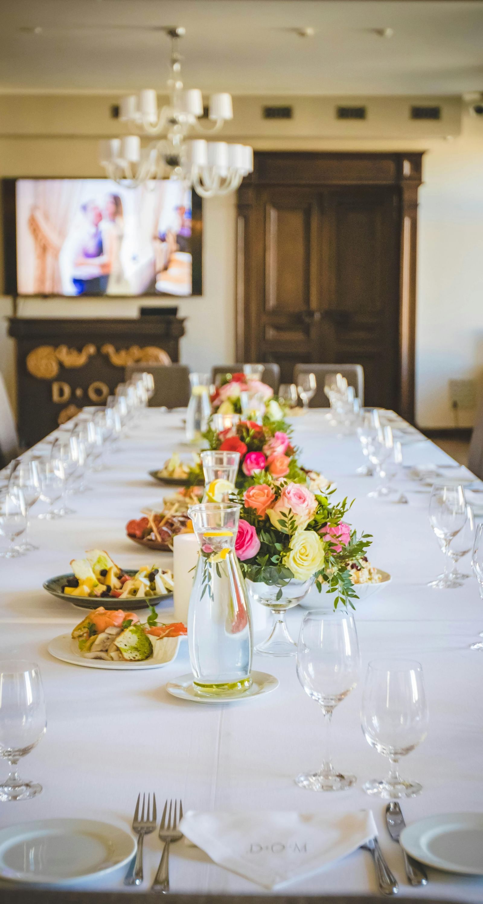 image of a closed space with an expansive dining table decorated with flowers and crockery