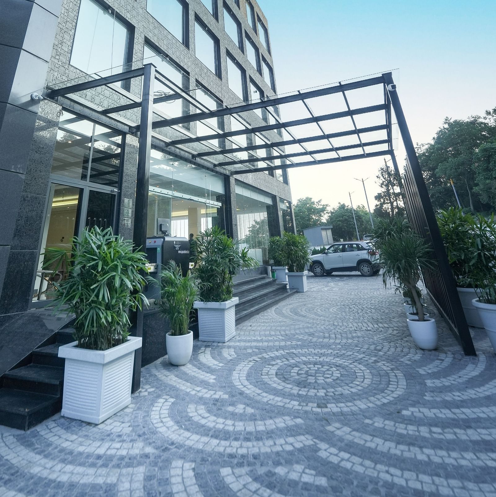 An image of a patterned pathway leading to the hotel entrance, flanked by potted plants on either side - NAMAMI BY ZENQ BANKHANDI