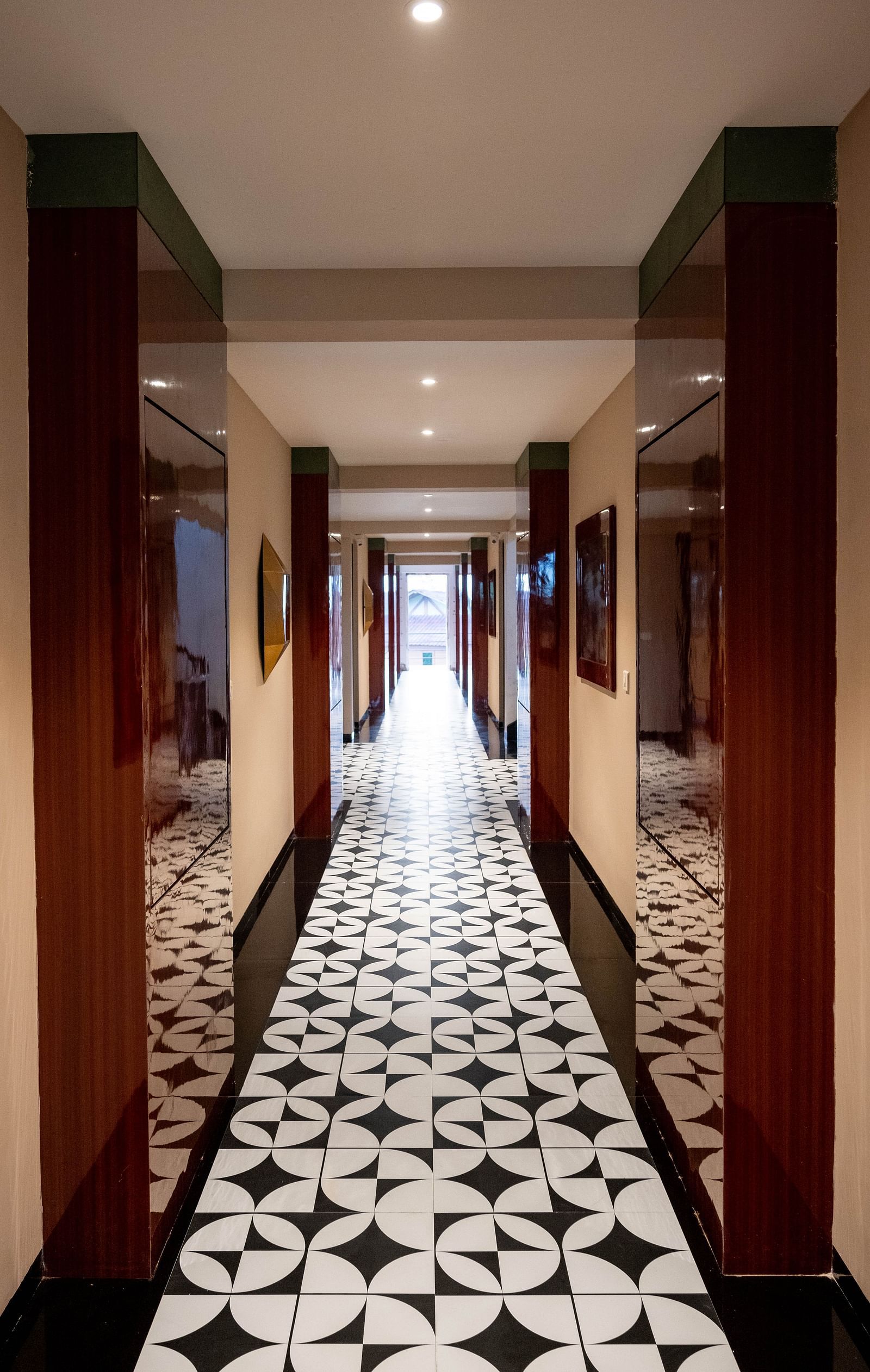 A portrait image of a corridor featuring designer marble flooring, accented by wooden wall decor and warm lighting
