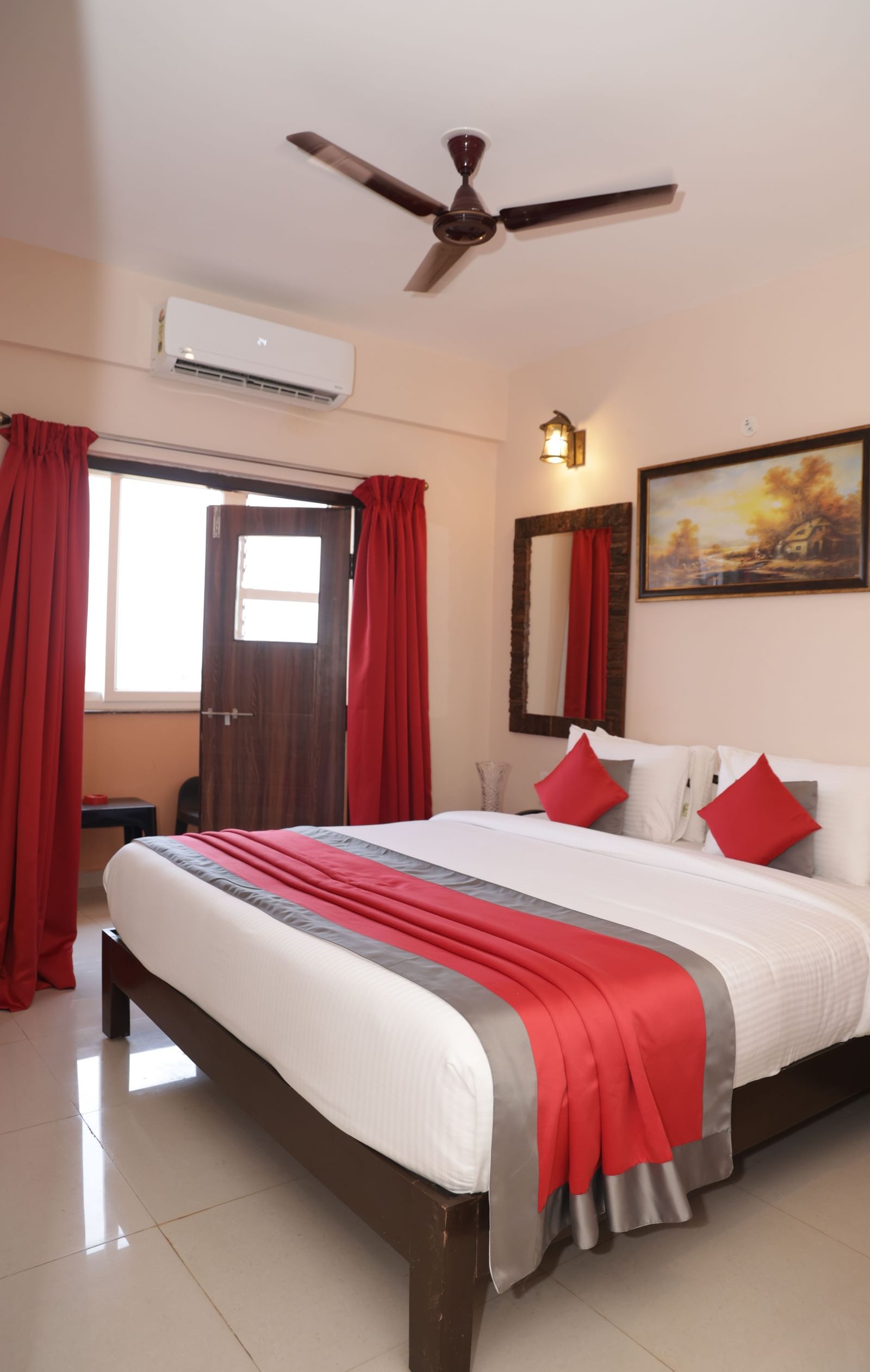 A bed near a window with curtains, wall art, bedside tables and ceiling fan at Nazri The Verda Hotel, Arambol.