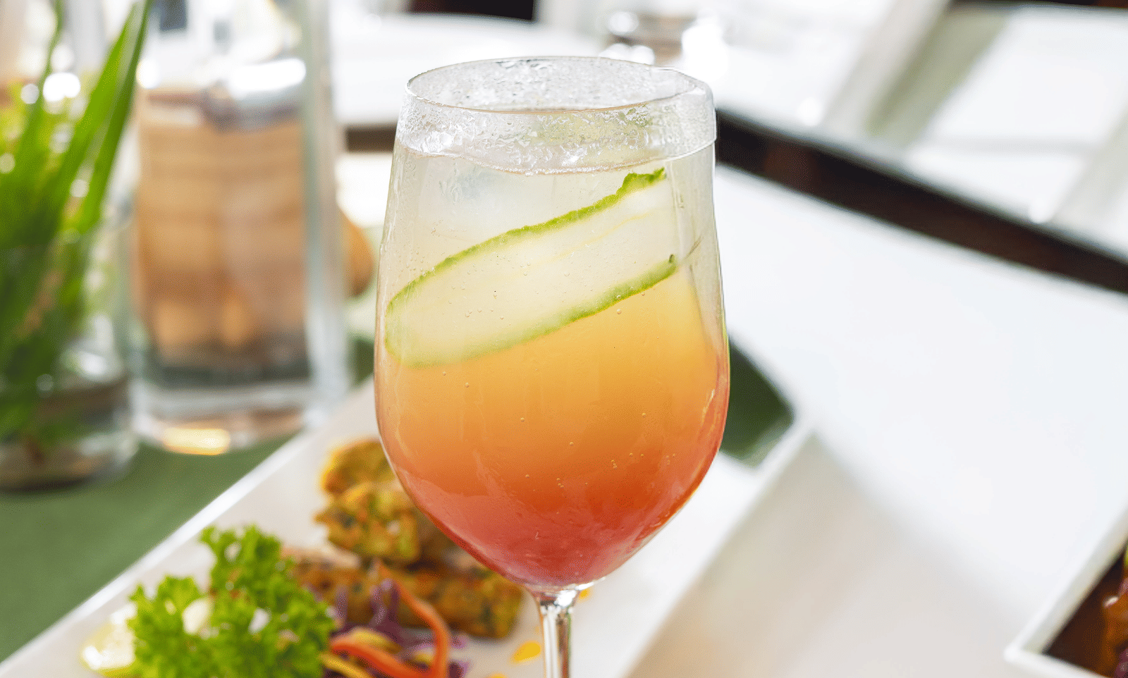 A refreshing orange drink and a small salad are presented in glassware on a glossy white surface - Megha Resort & Villas, Dehradun