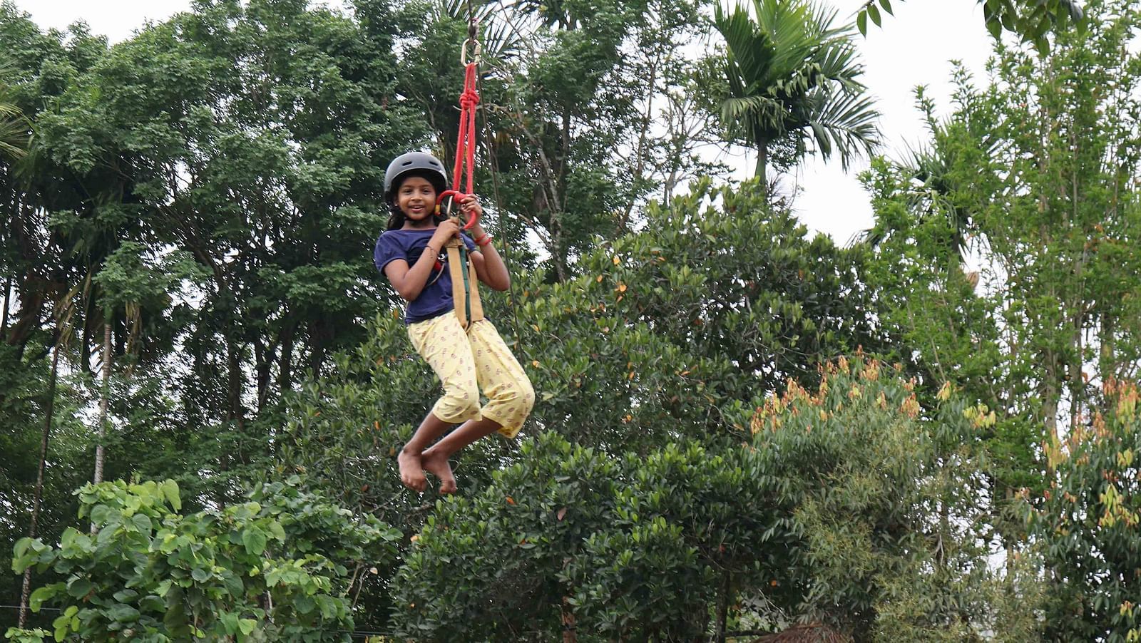 Image of a girl doing zip lining at the play area of our hotel | Great Trails Wayanad by  GRT hotels.