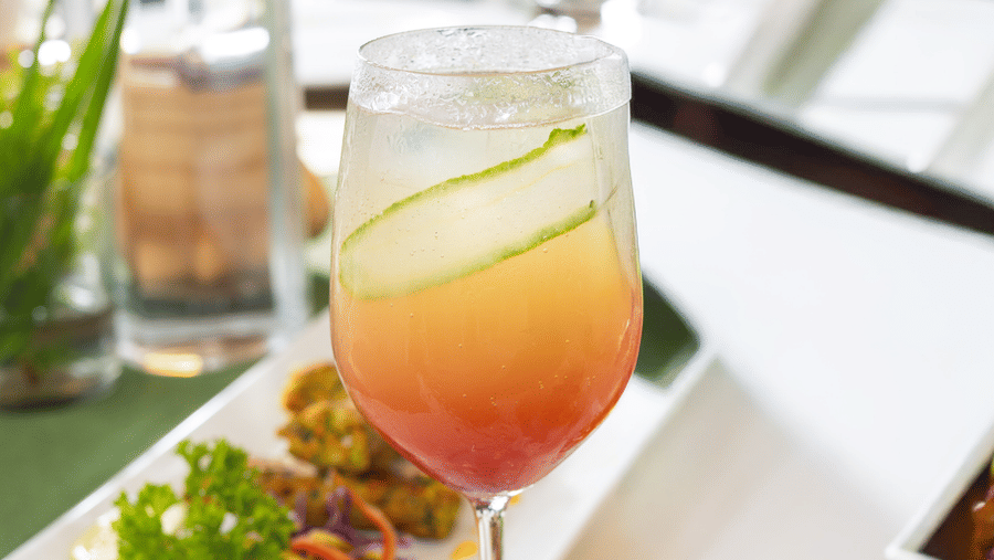 A refreshing orange drink and a small salad are presented in glassware on a glossy white surface - Megha Resort & Villas, Dehradun
