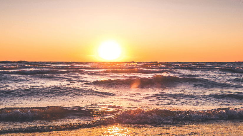 image of a beautiful sunset at a beach side with sun rays reflecting in the water