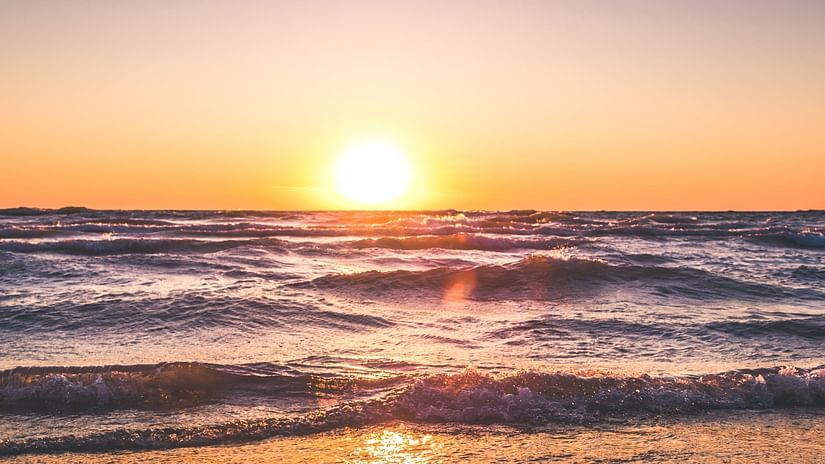 A serene sunset over the ocean with golden hues reflecting on the waves and wet sand