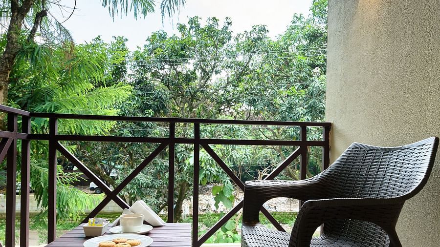 a chair and a small table in the balcony of the Superior Room at ABN Sarovar Portico, Jim Corbett