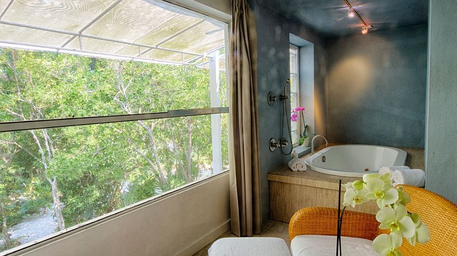 Seating area at Casa Morada with two white chairs, a round table, and a view of greenery through a large window.